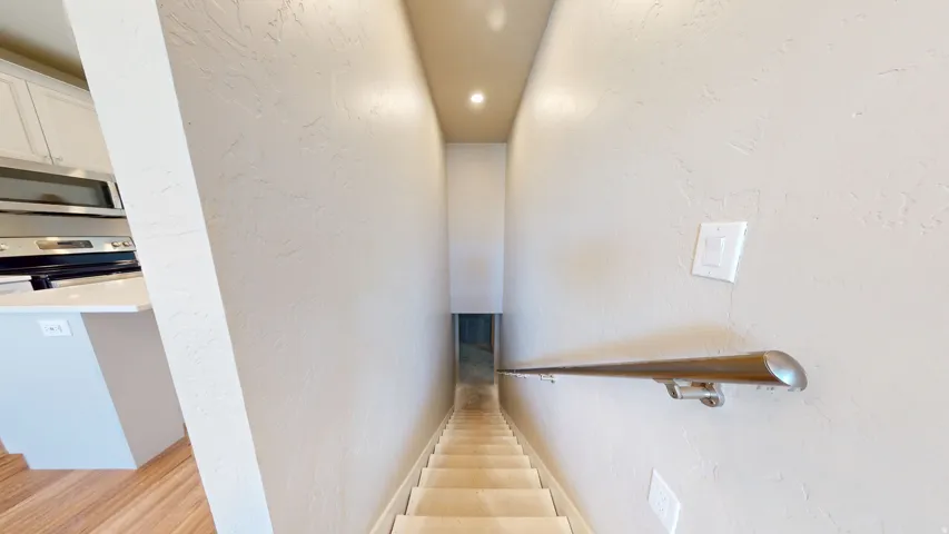 Stairway featuring a textured wall and recessed lighting
