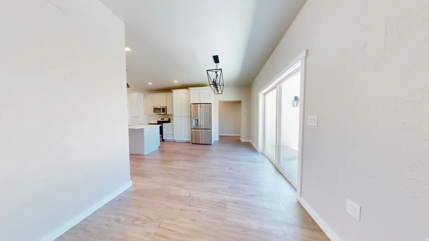 Hallway with light wood-style floors and recessed lighting