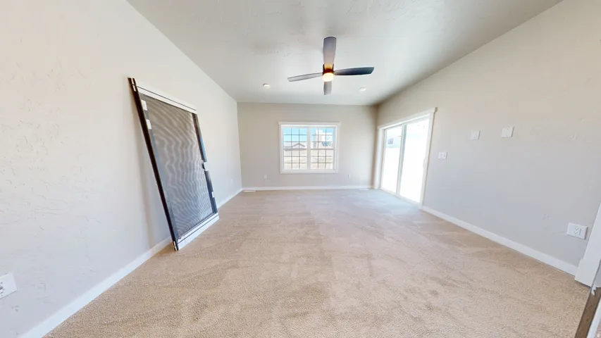 Empty room featuring light carpet, ceiling fan, and a textured wall