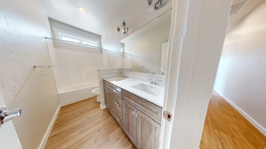 Full bathroom with double vanity, light wood-style flooring, and  shower combination