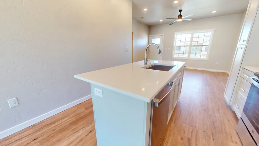 Kitchen with a kitchen island with sink, light wood-type flooring, stainless steel appliances, light stone countertops, and recessed lighting