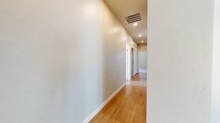Corridor featuring a textured wall, light wood finished floors, and recessed lighting