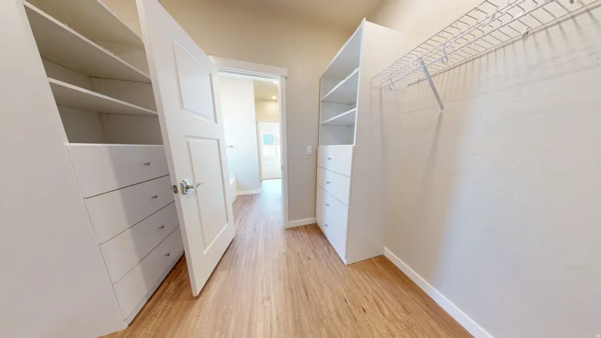 Walk in closet with light wood-type flooring