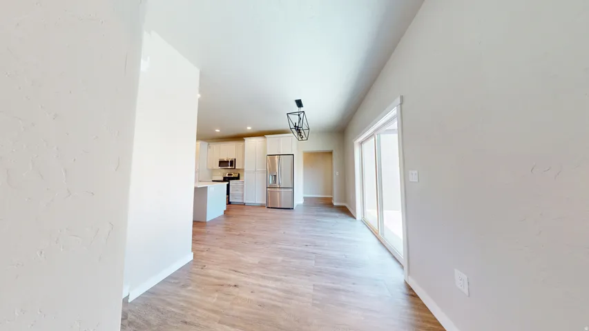 Corridor with light wood finished floors, a textured wall, and recessed lighting