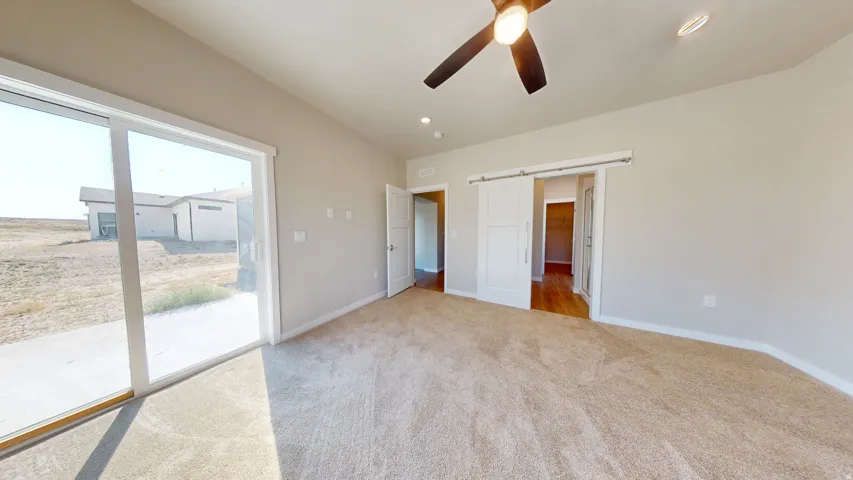 Unfurnished bedroom featuring a barn door, light colored carpet, access to outside, a ceiling fan, and recessed lighting