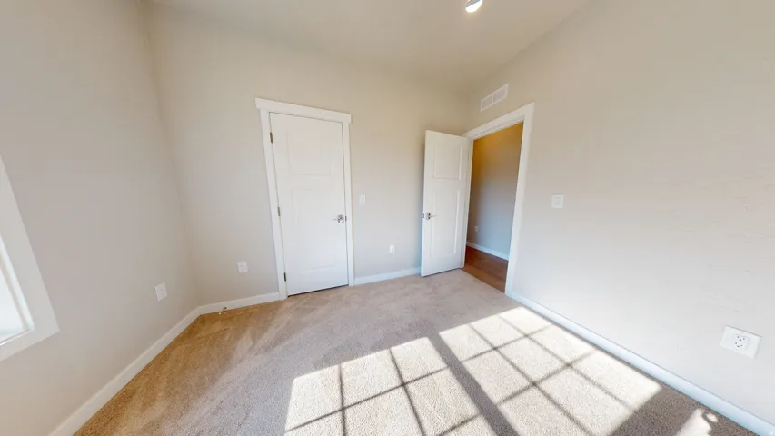 Unfurnished bedroom featuring light carpet and baseboards
