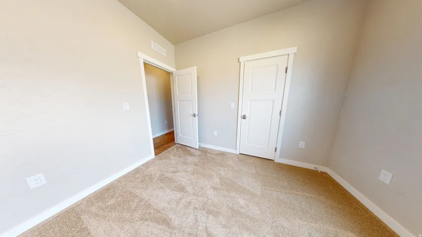 Unfurnished bedroom with carpet flooring and baseboards