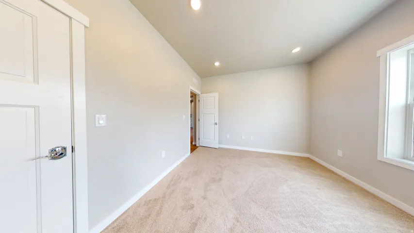Empty room with recessed lighting and light colored carpet