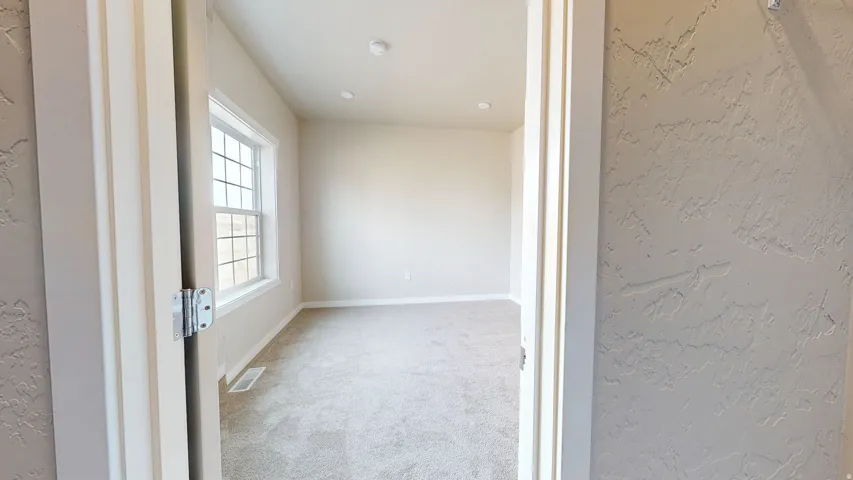Empty room featuring a textured wall and carpet