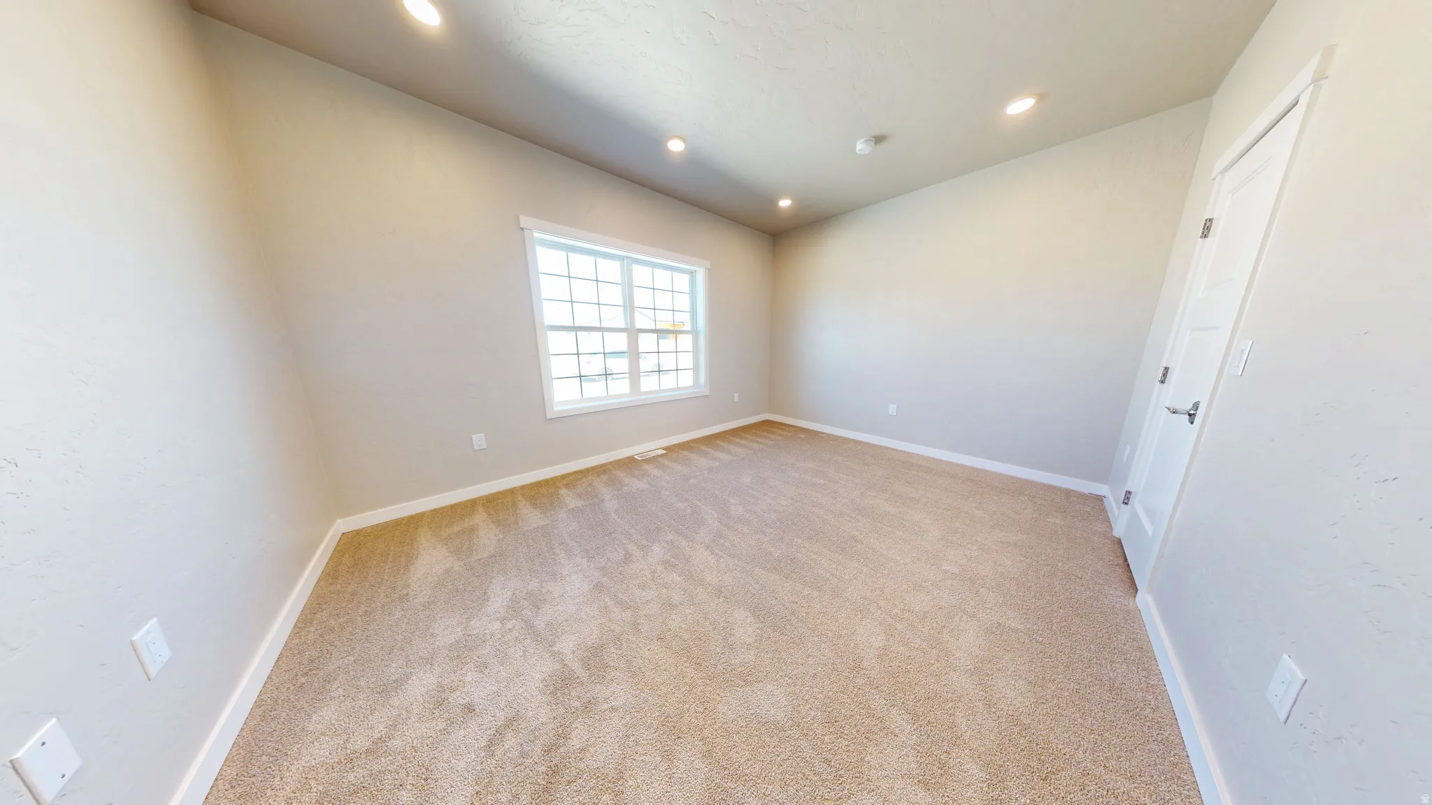 Empty room with light colored carpet and recessed lighting