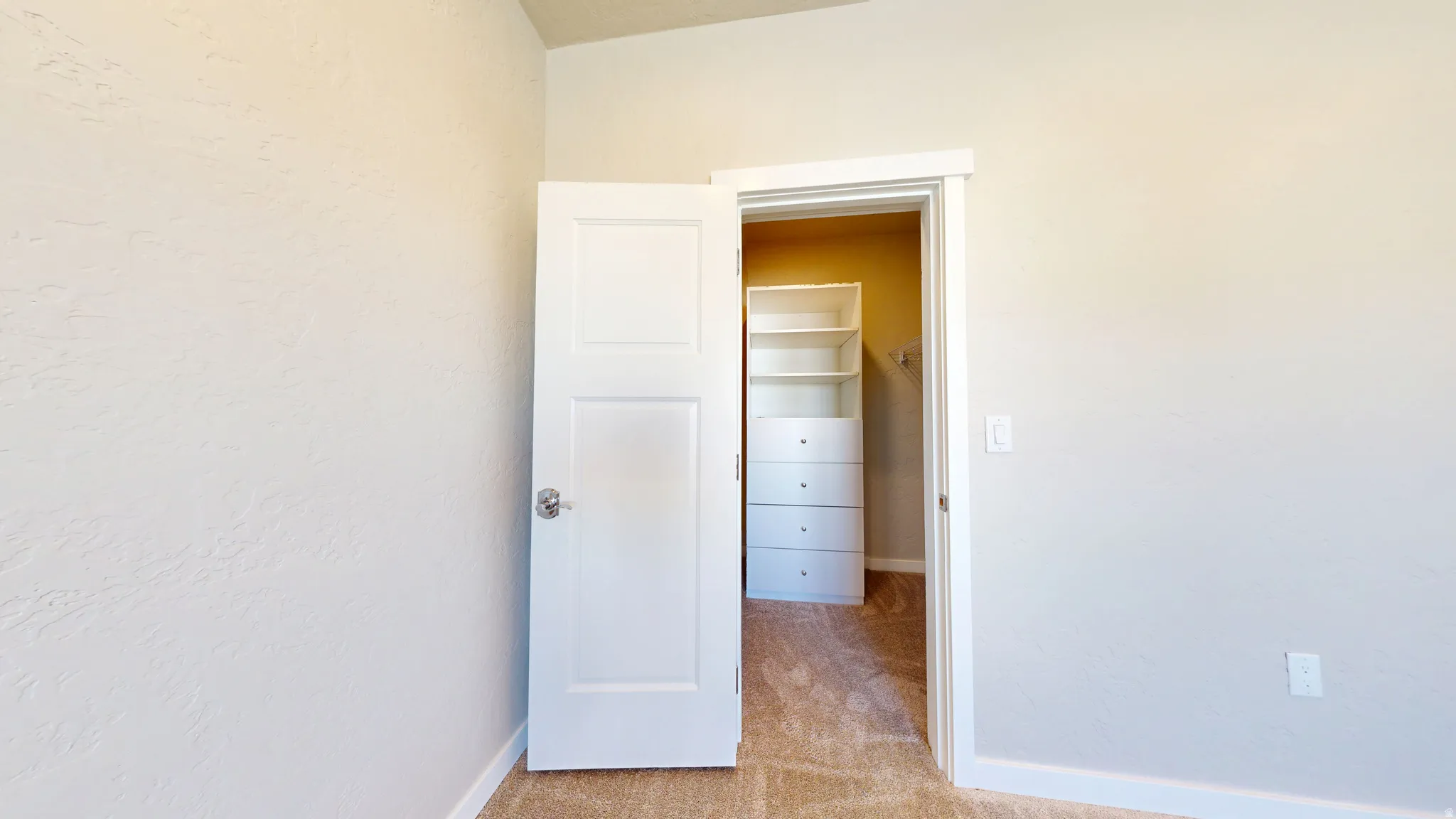Unfurnished bedroom with a spacious closet and light colored carpet