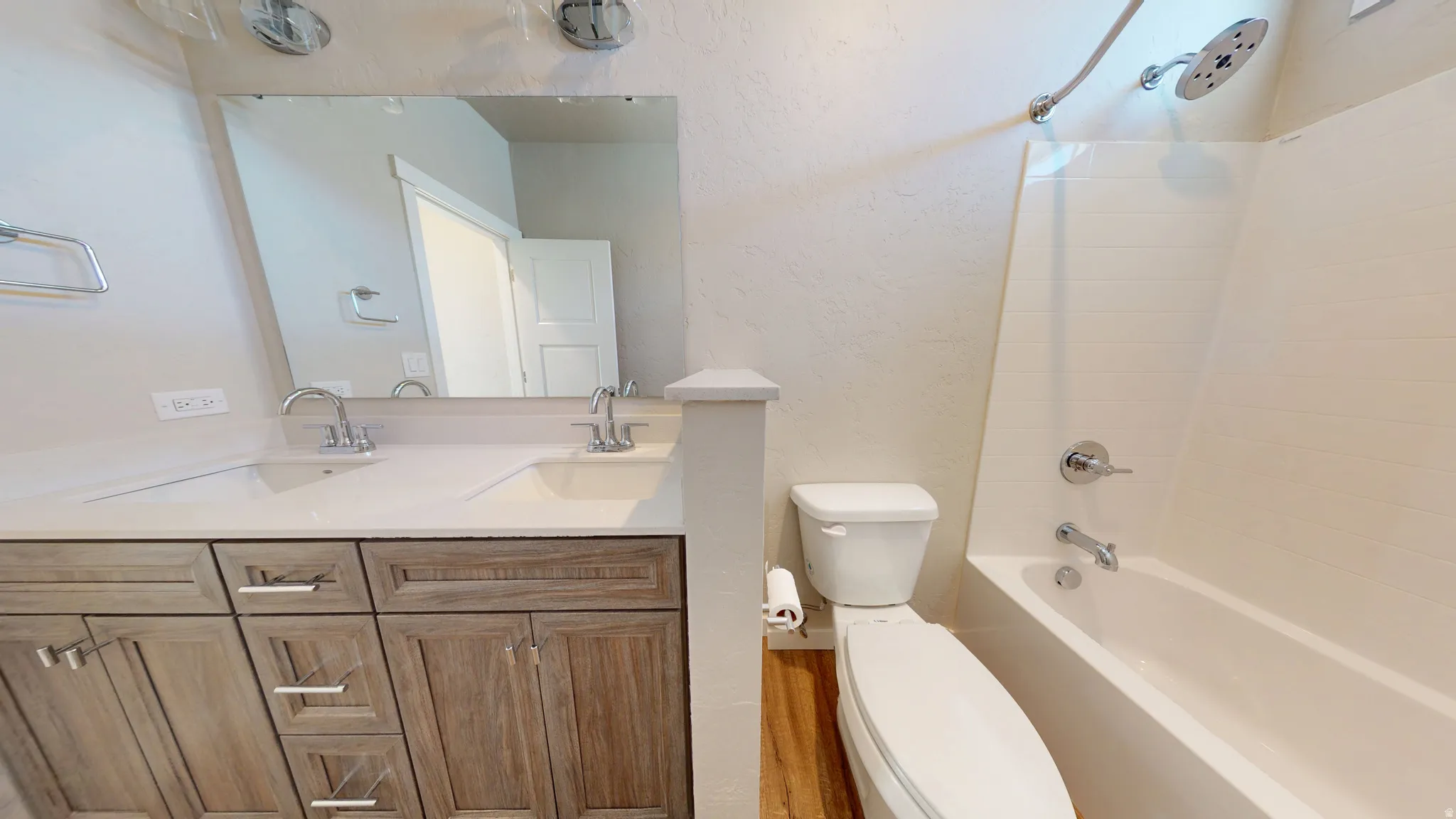 Full bath featuring double vanity, a textured wall, and  shower combination