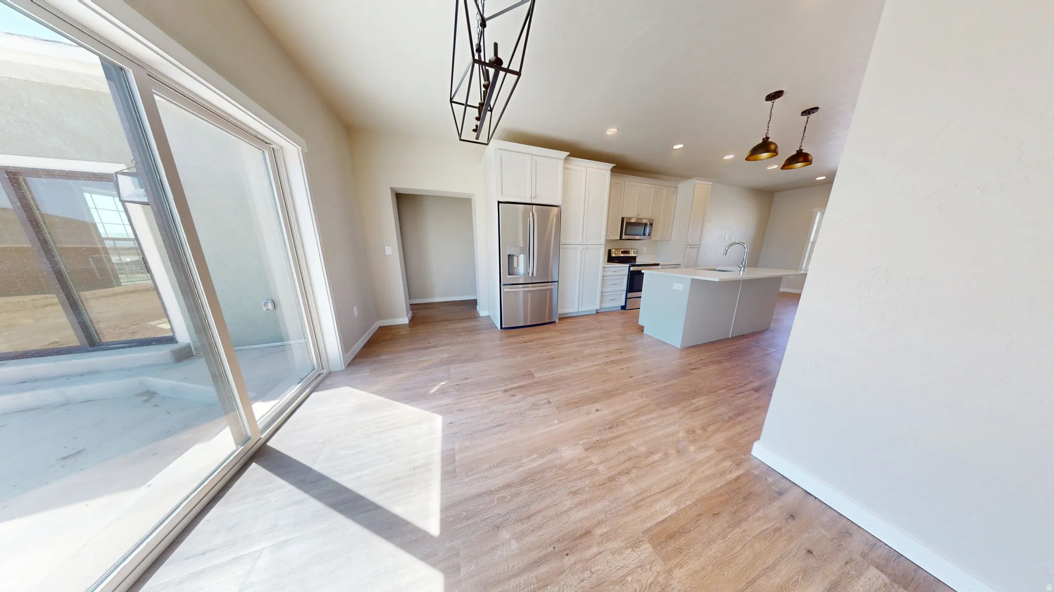 Kitchen featuring stainless steel appliances, decorative light fixtures, light wood-style flooring, white cabinetry, and recessed lighting
