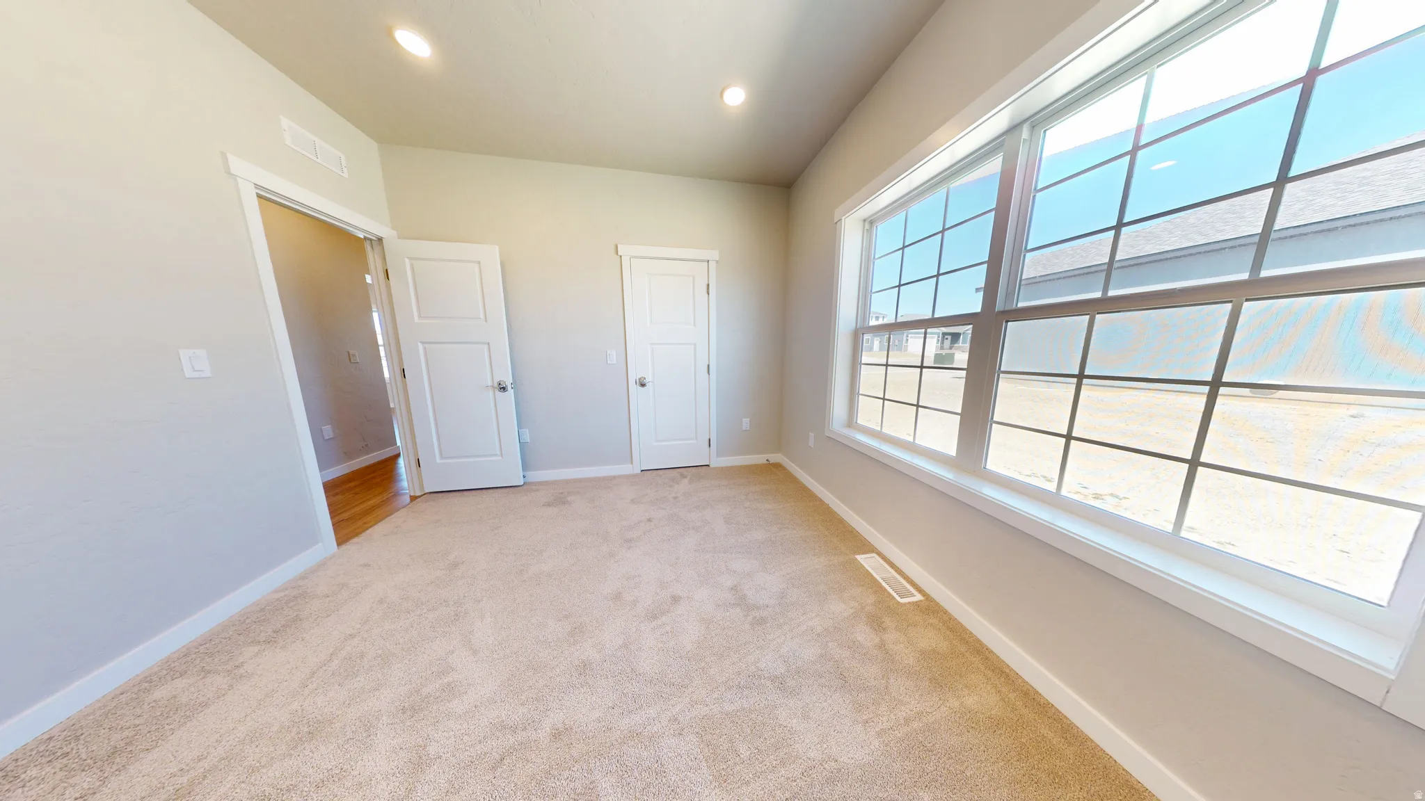 Unfurnished bedroom with light colored carpet and recessed lighting