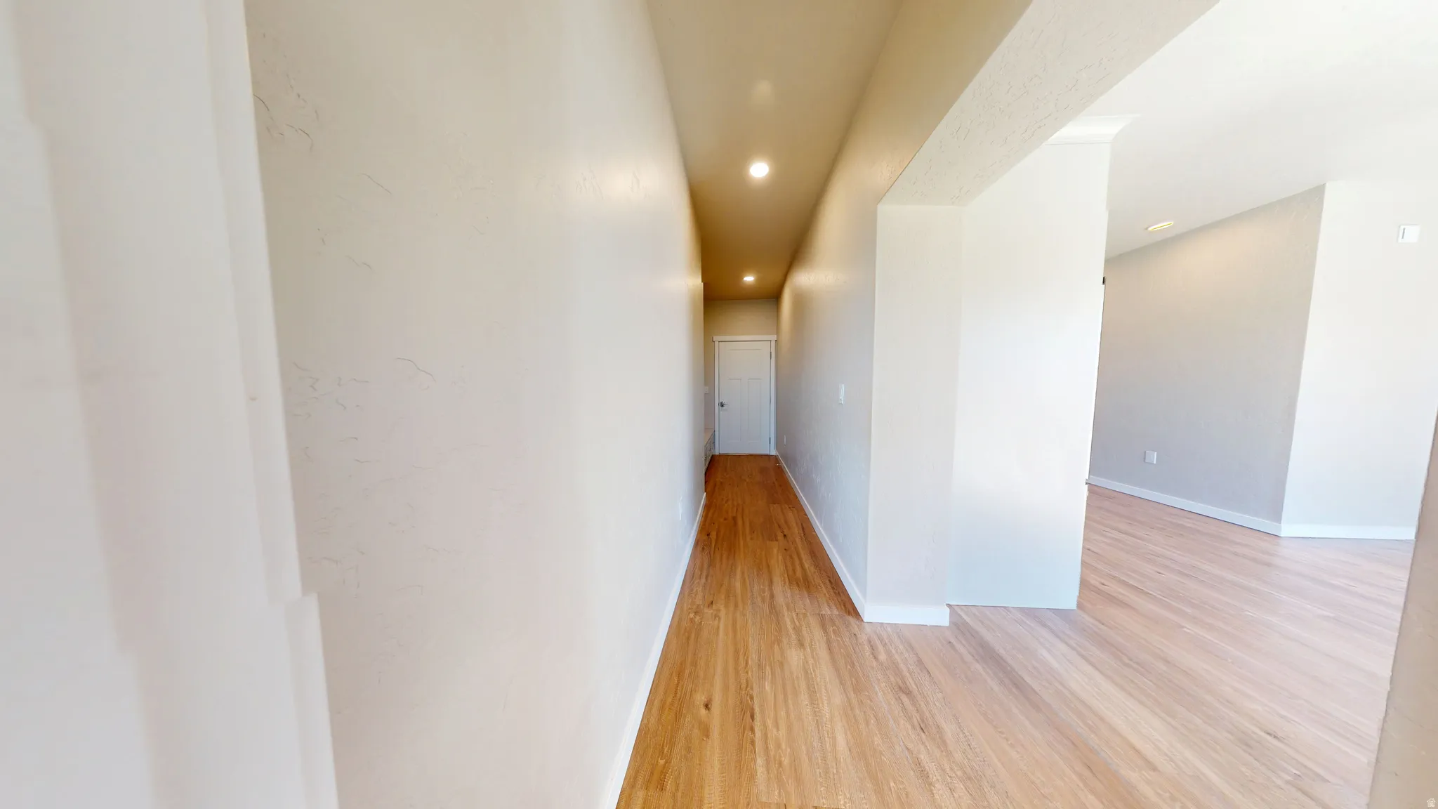 Hall with light wood-type flooring and recessed lighting