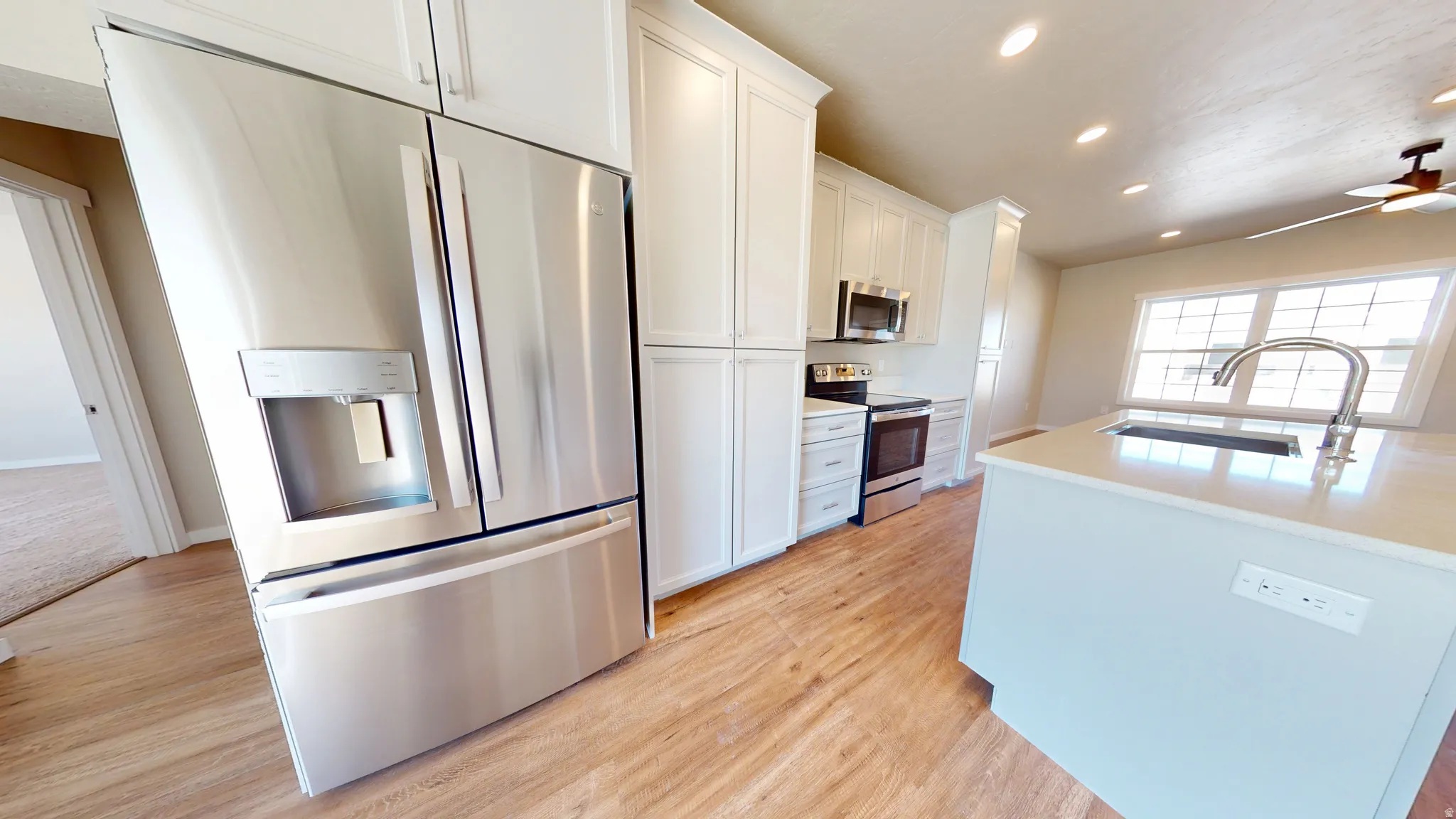 Kitchen featuring appliances with stainless steel finishes, recessed lighting, white cabinets, light wood-type flooring, and a ceiling fan