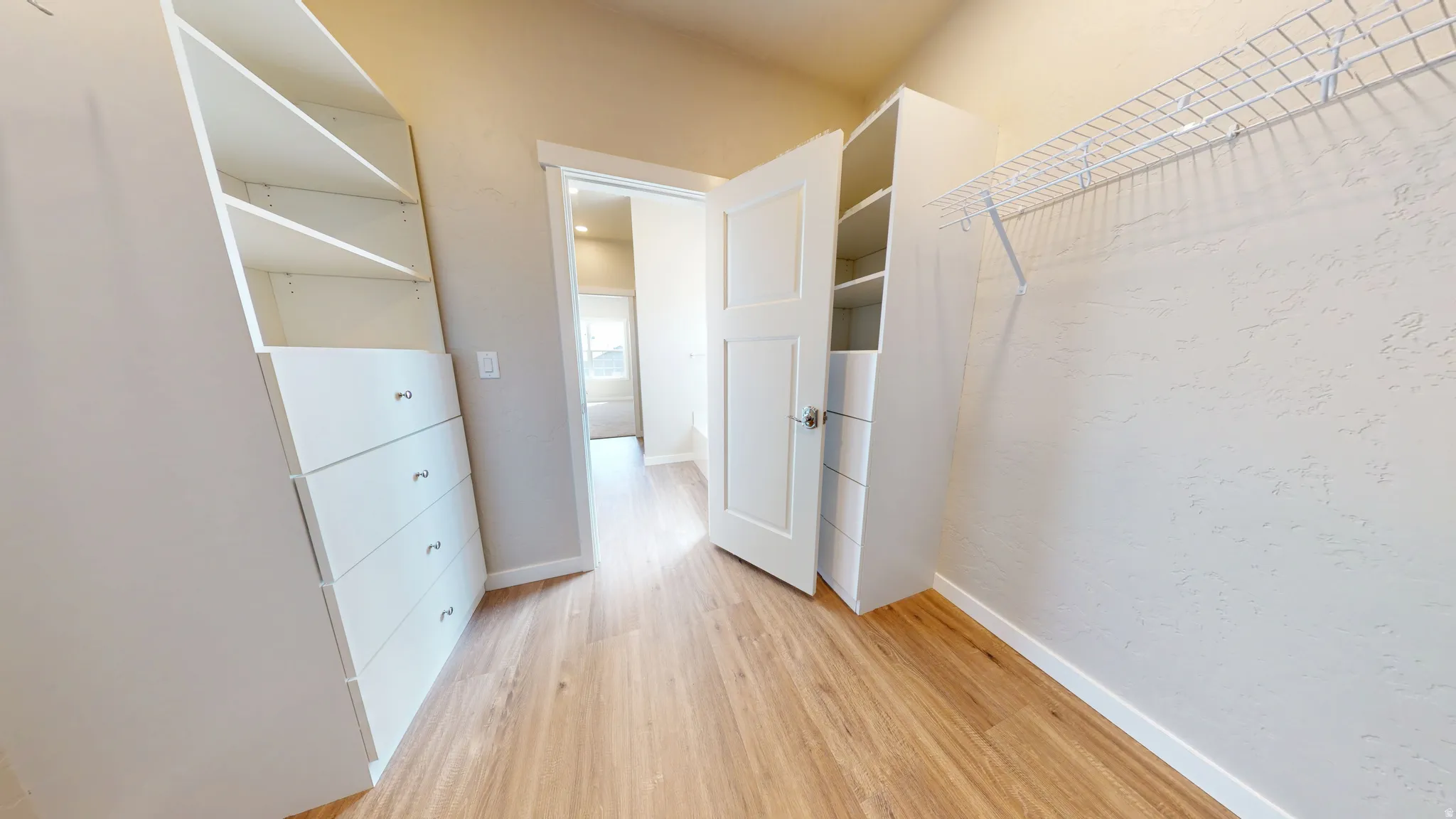 Walk in closet with light wood-style flooring