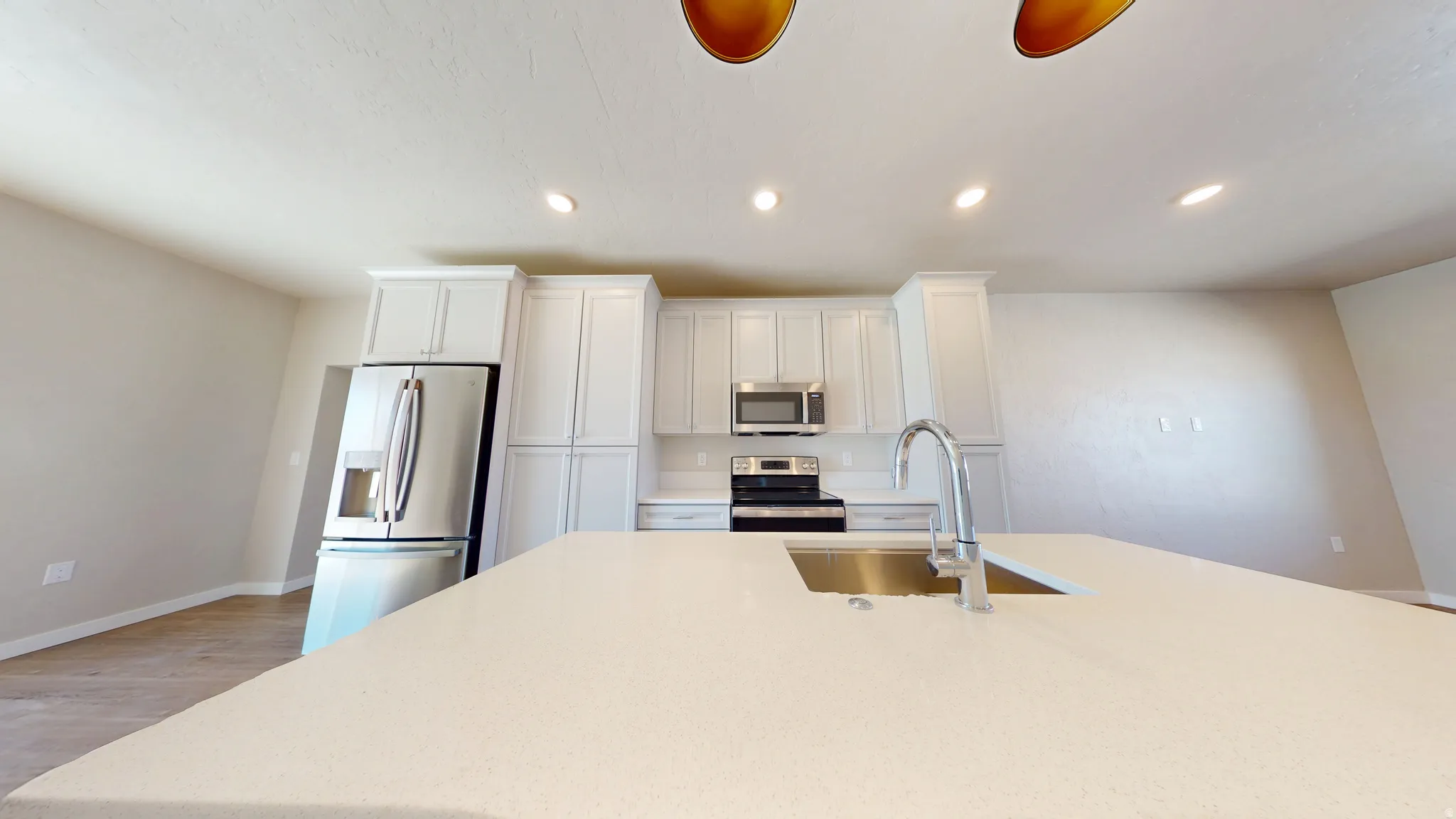 Kitchen featuring recessed lighting, appliances with stainless steel finishes, light wood-style floors, white cabinets, and light stone countertops