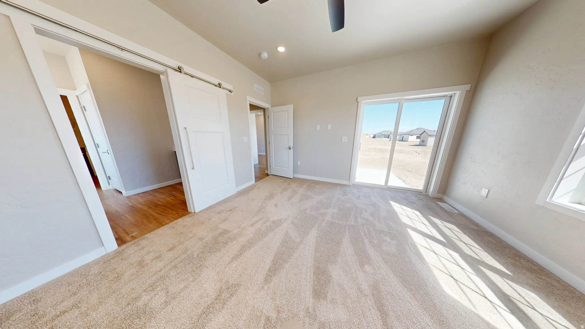Unfurnished bedroom featuring a barn door, light carpet, a ceiling fan, and recessed lighting