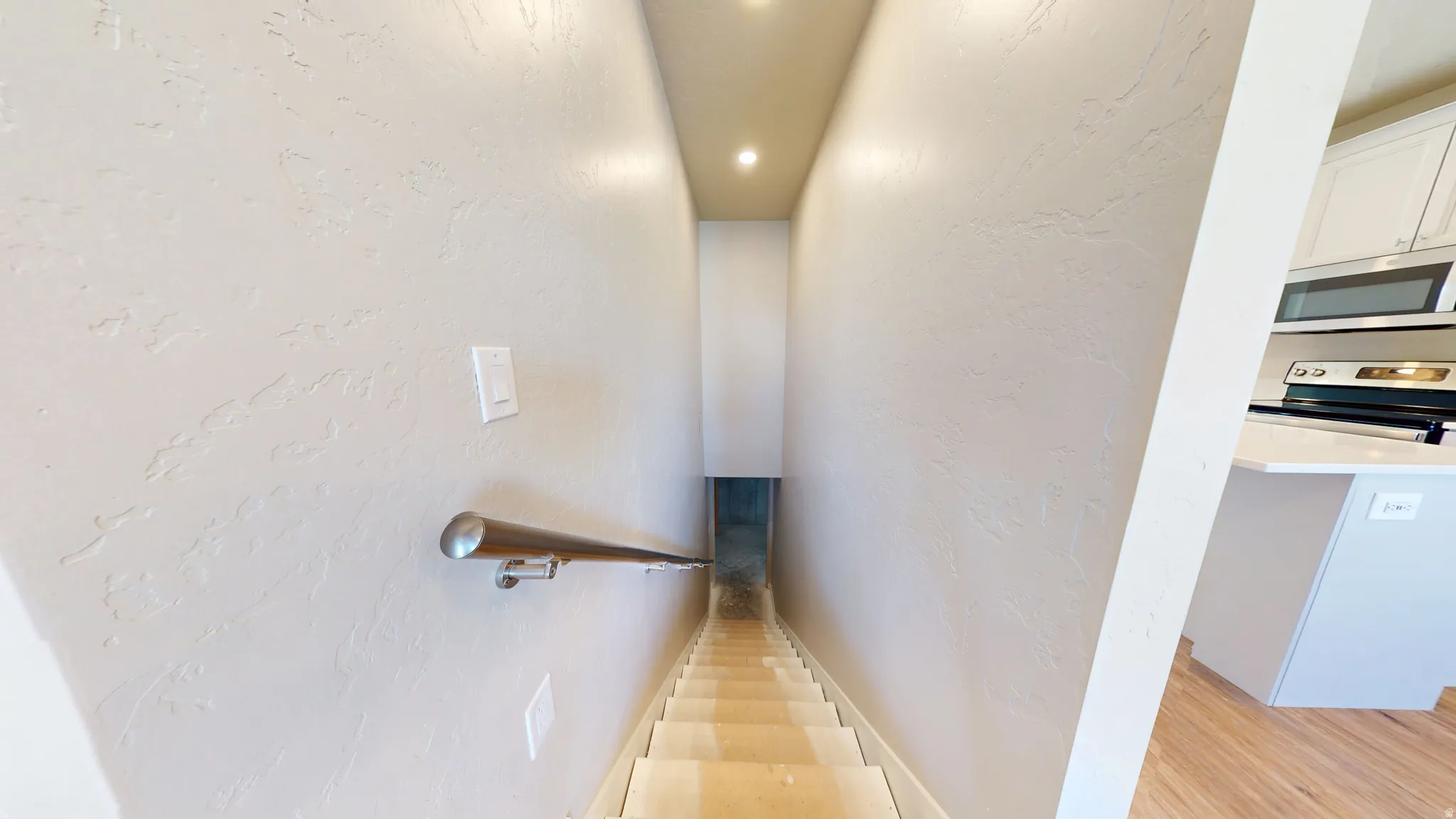 Staircase with a textured wall and recessed lighting