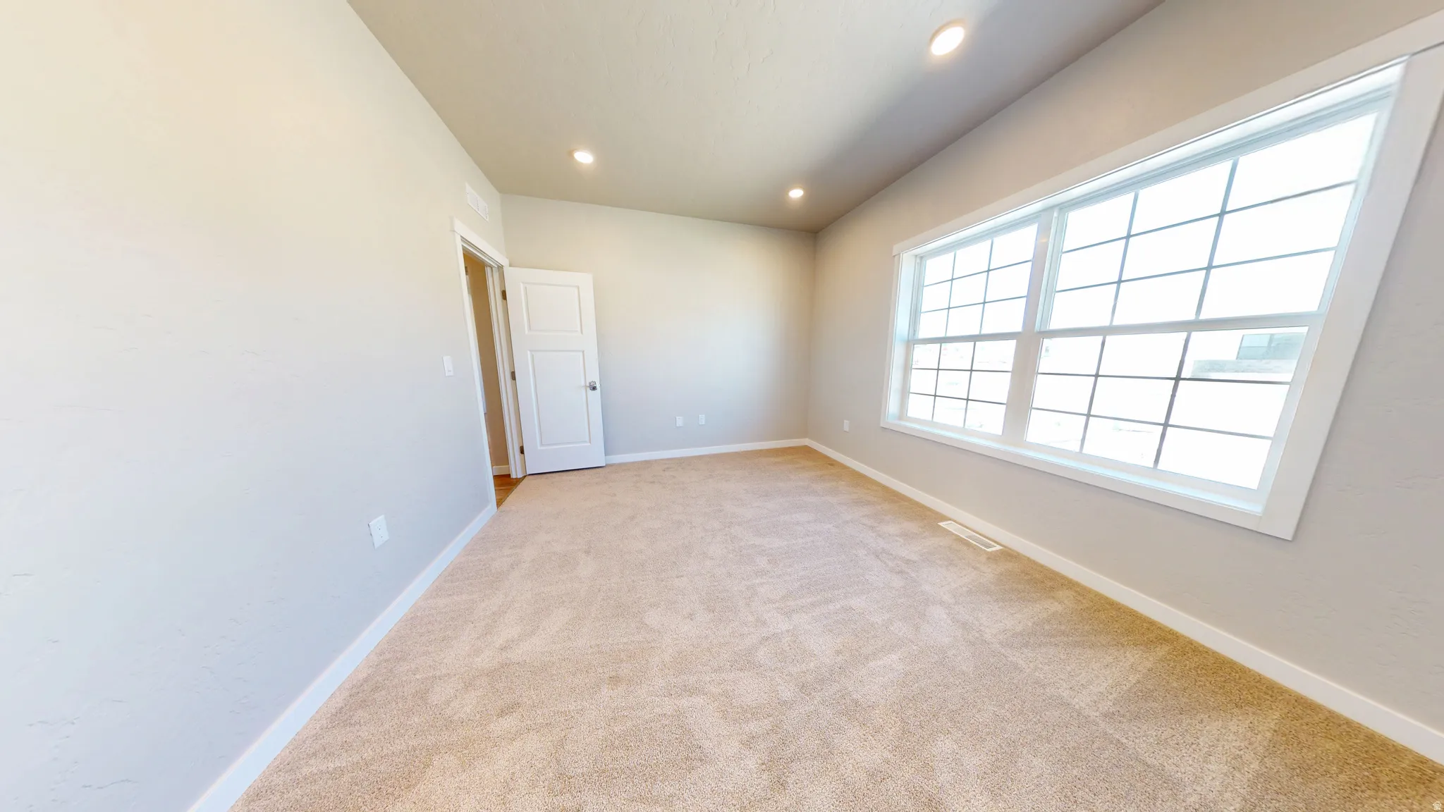 Empty room with light colored carpet and recessed lighting
