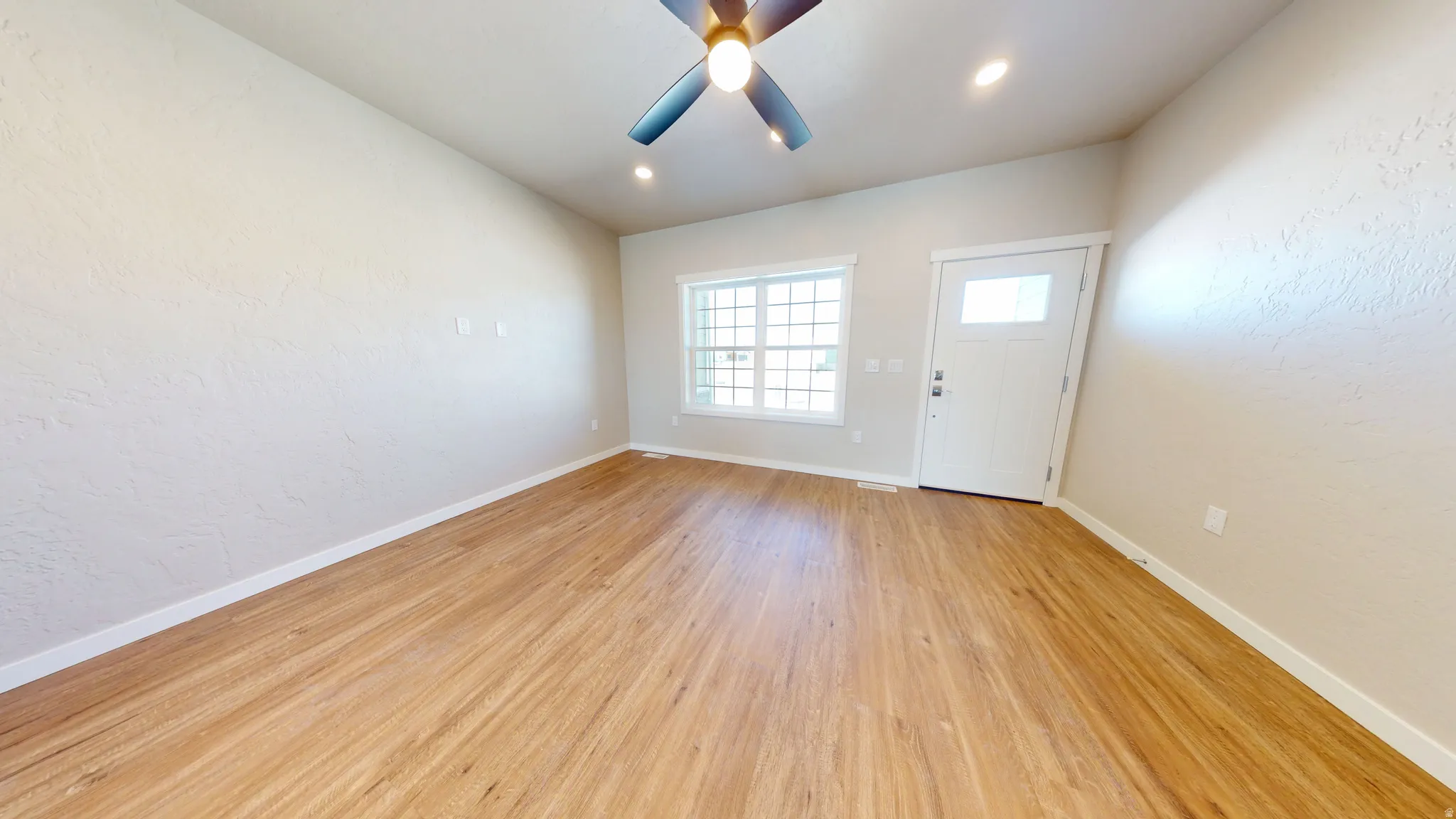 Foyer with a textured wall, light wood-style flooring, ceiling fan, and recessed lighting