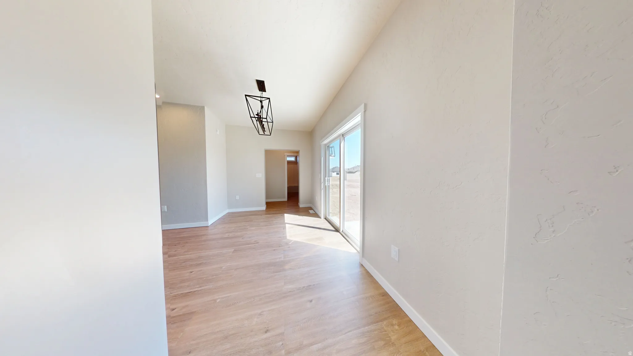Hallway with light wood-style floors and a chandelier