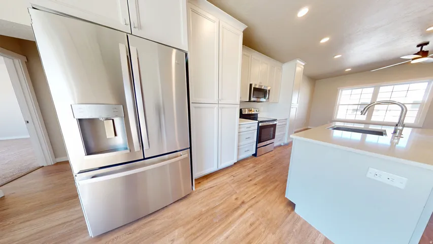 Kitchen featuring appliances with stainless steel finishes, recessed lighting, white cabinets, light wood-type flooring, and a ceiling fan