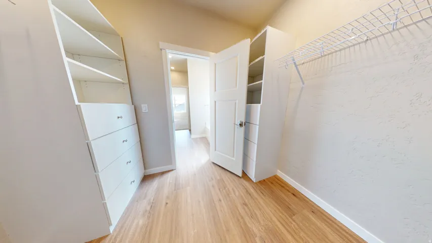 Walk in closet with light wood-style flooring