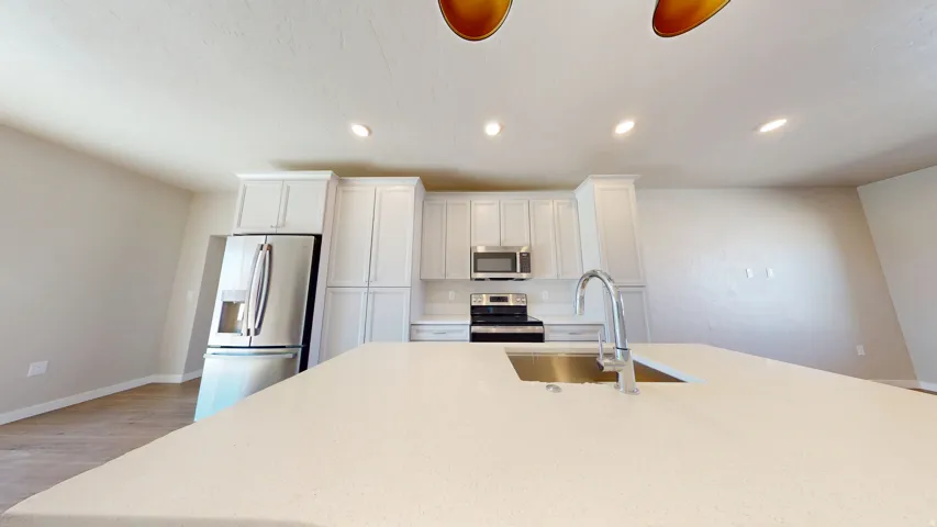 Kitchen featuring recessed lighting, appliances with stainless steel finishes, light wood-style floors, white cabinets, and light stone countertops
