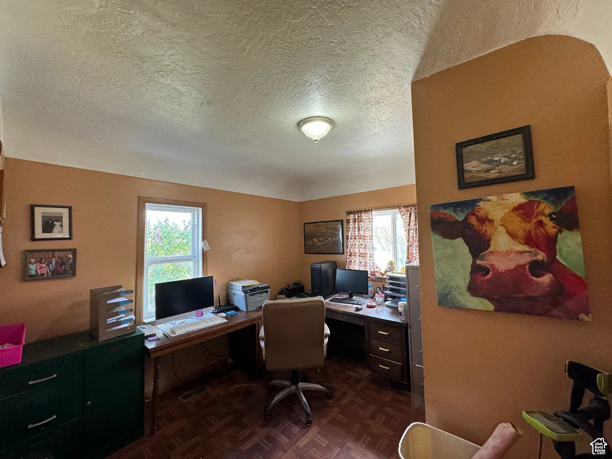 Home office featuring a textured ceiling, dark parquet floors, and plenty of natural light