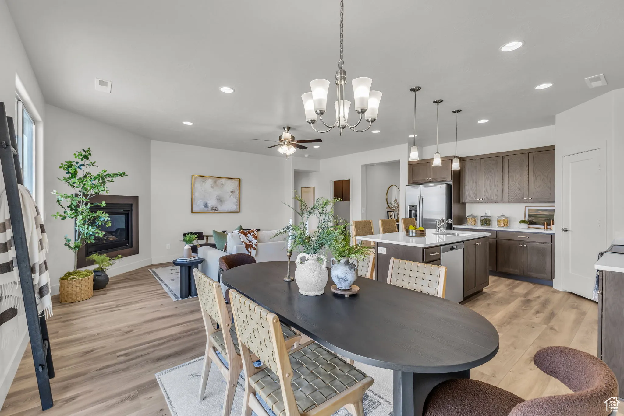 Dining space featuring ceiling fan with notable chandelier, light wood-type flooring, and sink