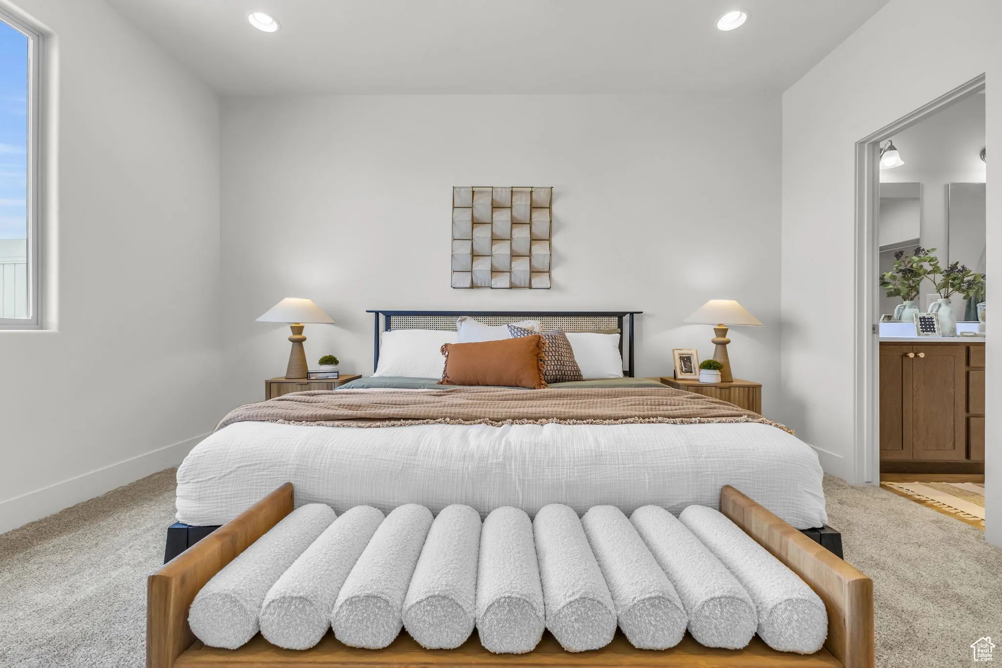 Carpeted bedroom featuring ensuite bath and multiple windows