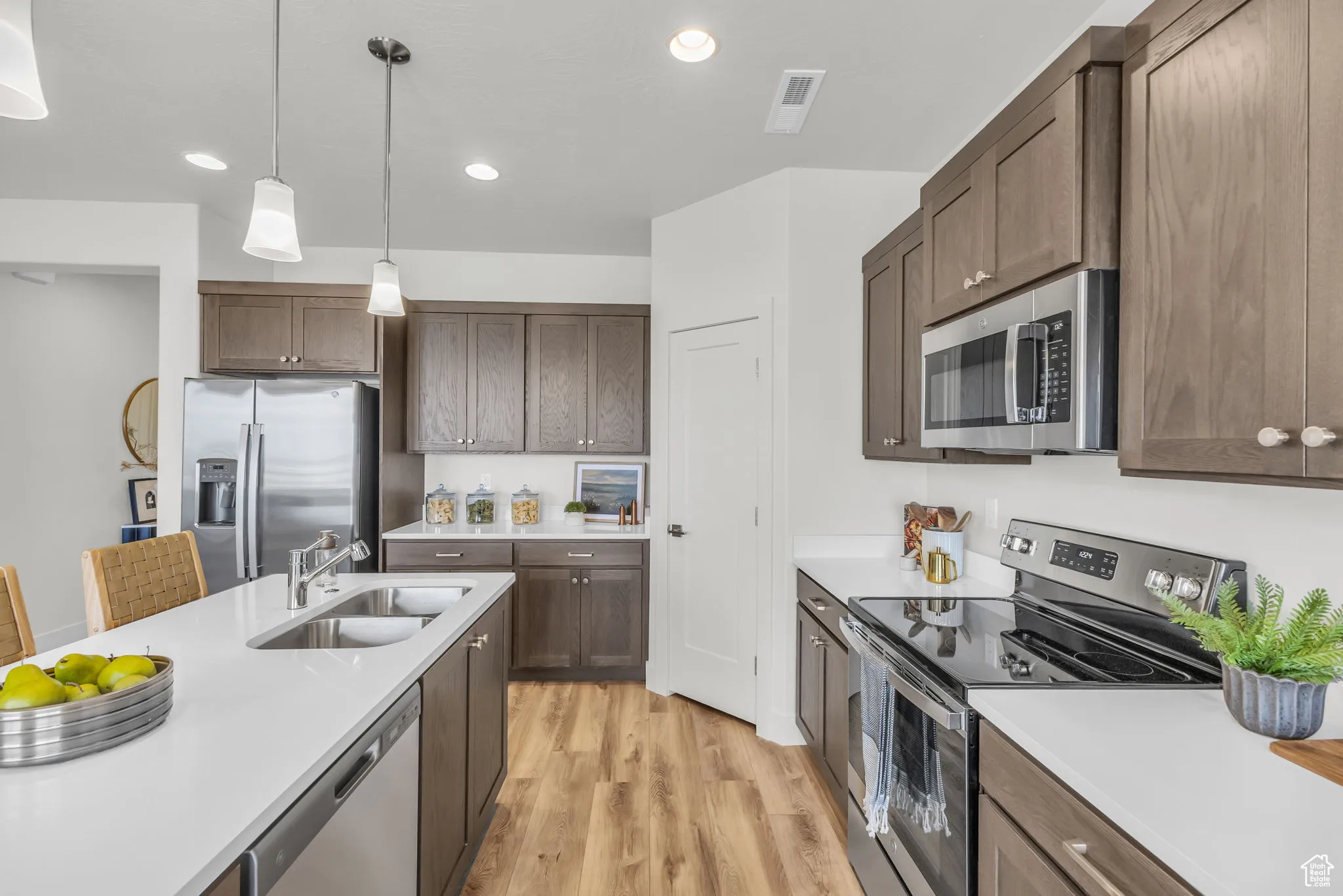 Kitchen featuring pendant lighting, a breakfast bar, sink, light hardwood / wood-style flooring, and appliances with stainless steel finishes