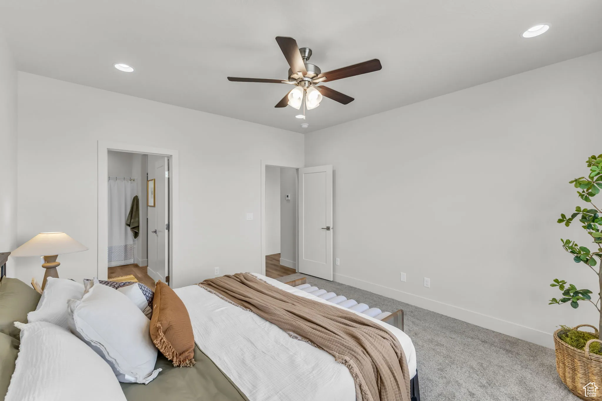 Carpeted bedroom featuring ensuite bath and ceiling fan
