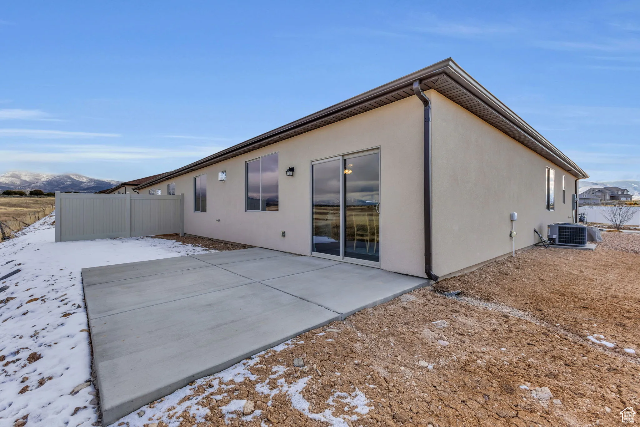 Snow covered rear of property featuring a mountain view, a patio, and central AC unit