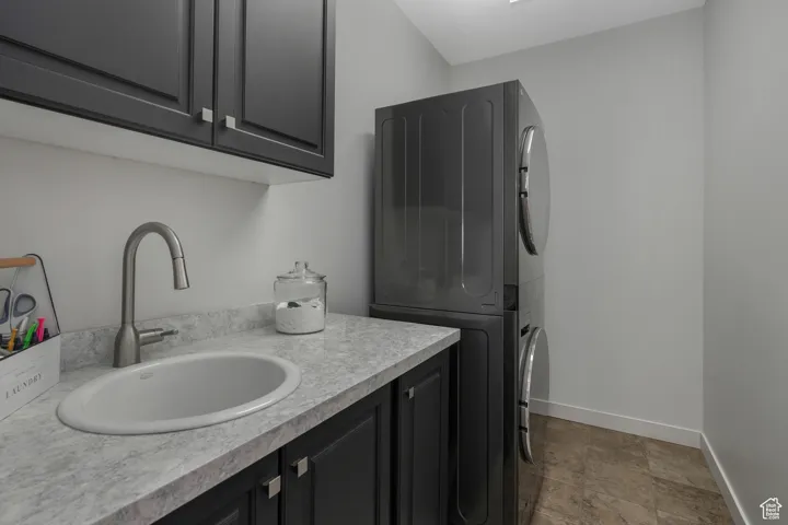 Laundry room featuring sink and stacked washer and clothes dryer