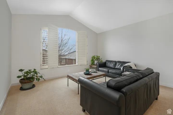 Carpeted living room featuring vaulted ceiling