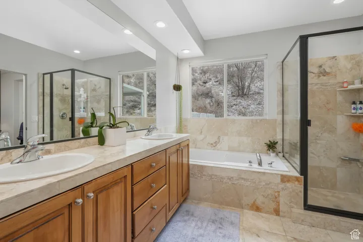 Bathroom featuring shower with separate bathtub, vanity, and a wealth of natural light