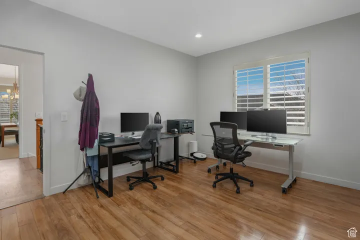 Office with light wood-type flooring and a chandelier