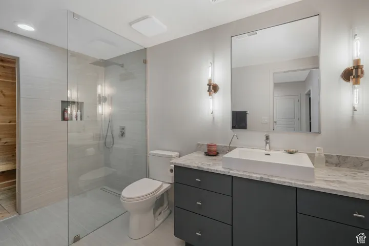 Bathroom featuring vanity, toilet, and tiled shower
