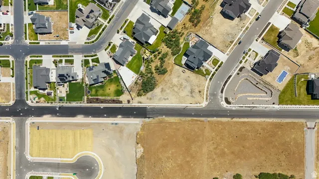 Developed residential neighborhood featuring paved streets, established homes with dark roofs, manicured lawns, and an in-ground swimming pool