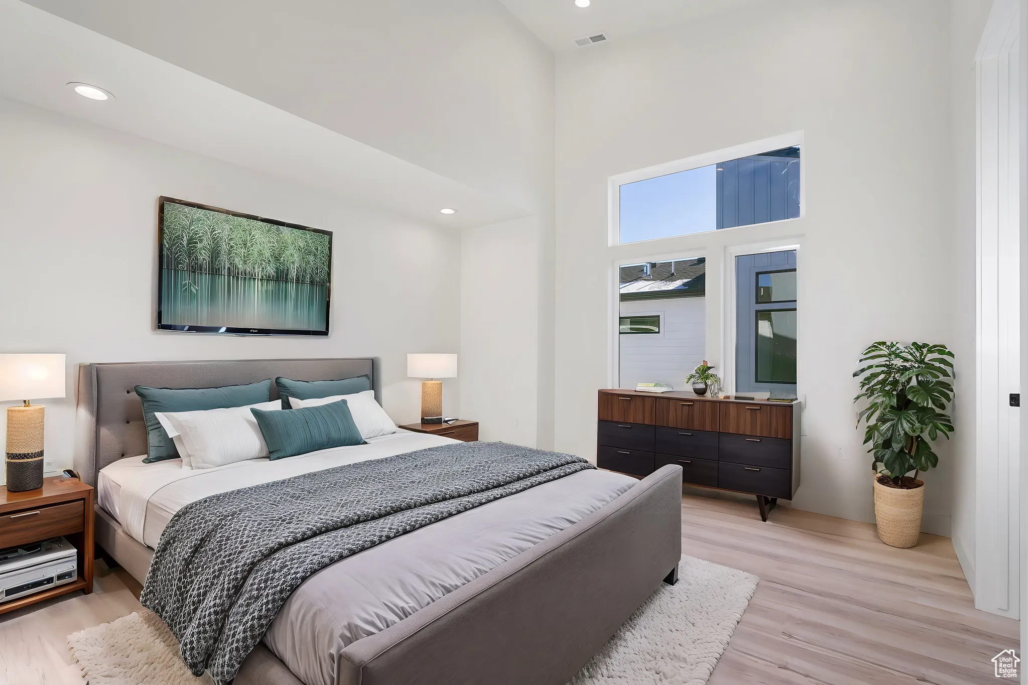 Bedroom with a towering ceiling and light hardwood / wood-style flooring
