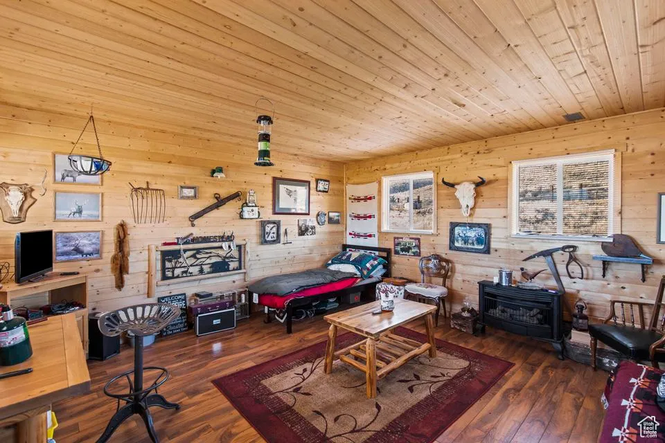 Rec room featuring a wood stove, wood ceiling, wood walls, and hardwood / wood-style floors