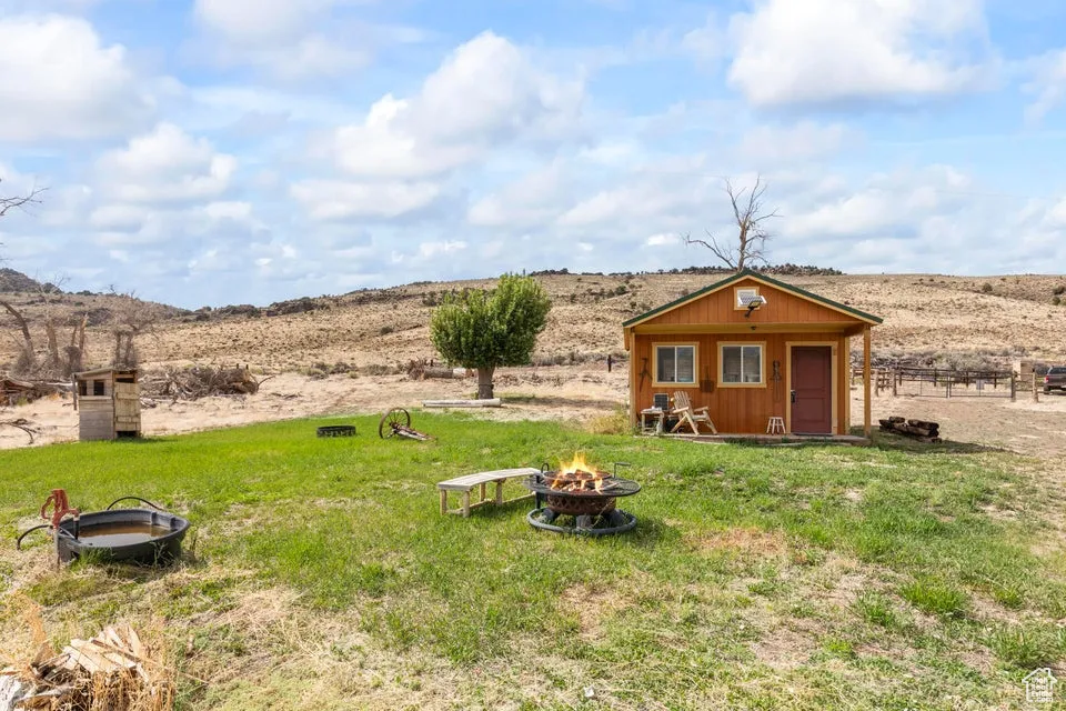View of yard with a fire pit, an outbuilding, and a rural view