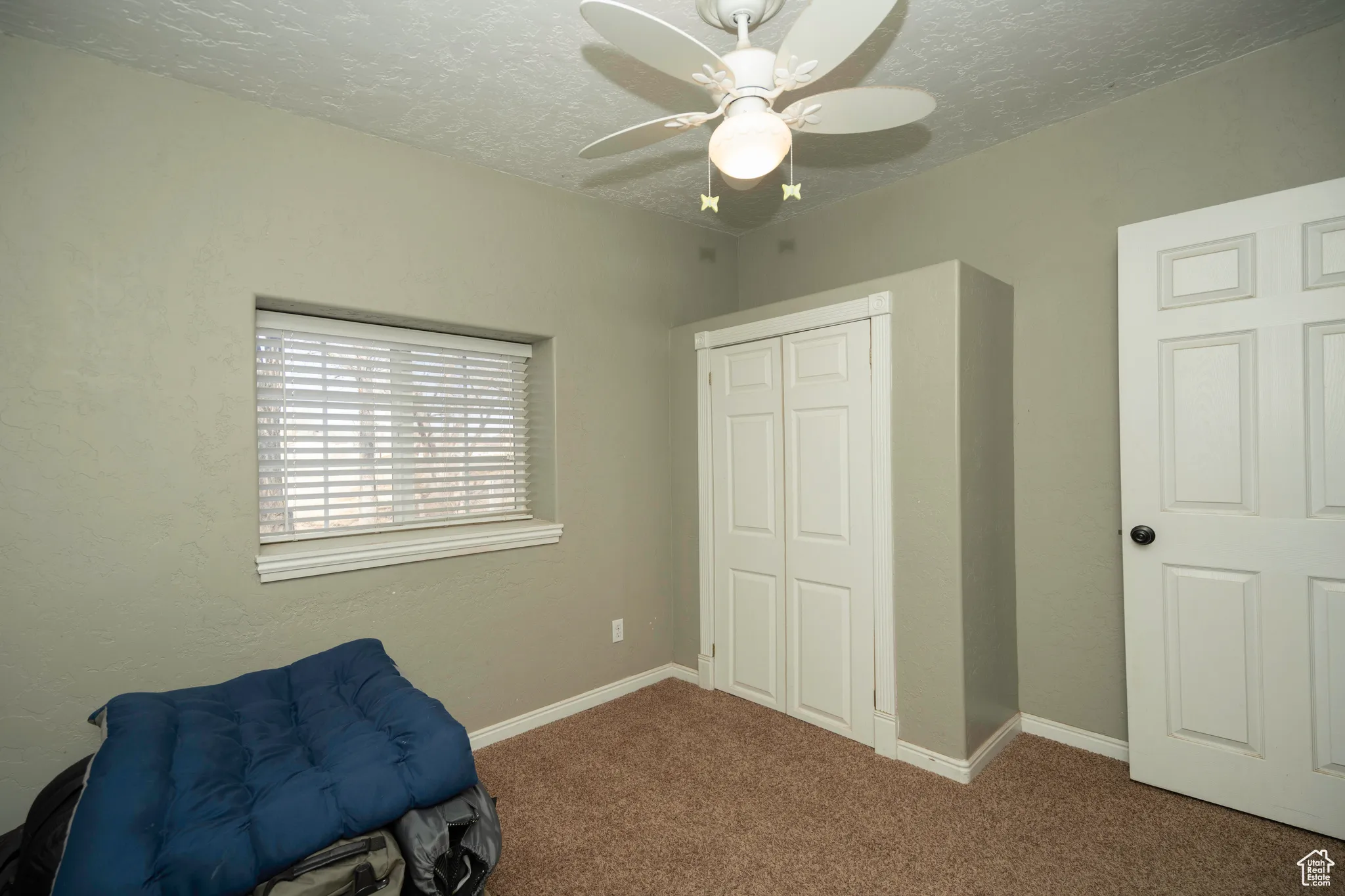 Bedroom with carpet floors, a textured ceiling, ceiling fan, and a closet