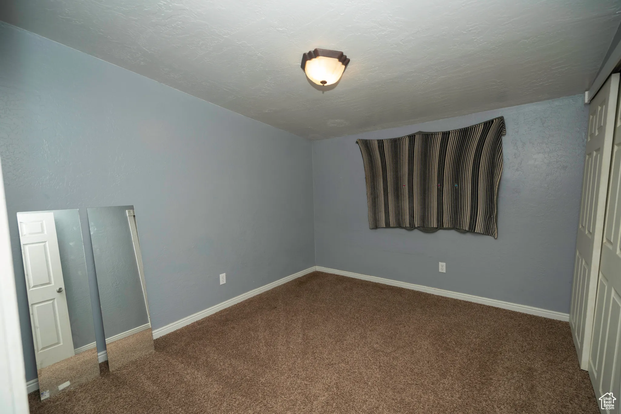 Unfurnished bedroom with carpet, a textured ceiling, and a closet