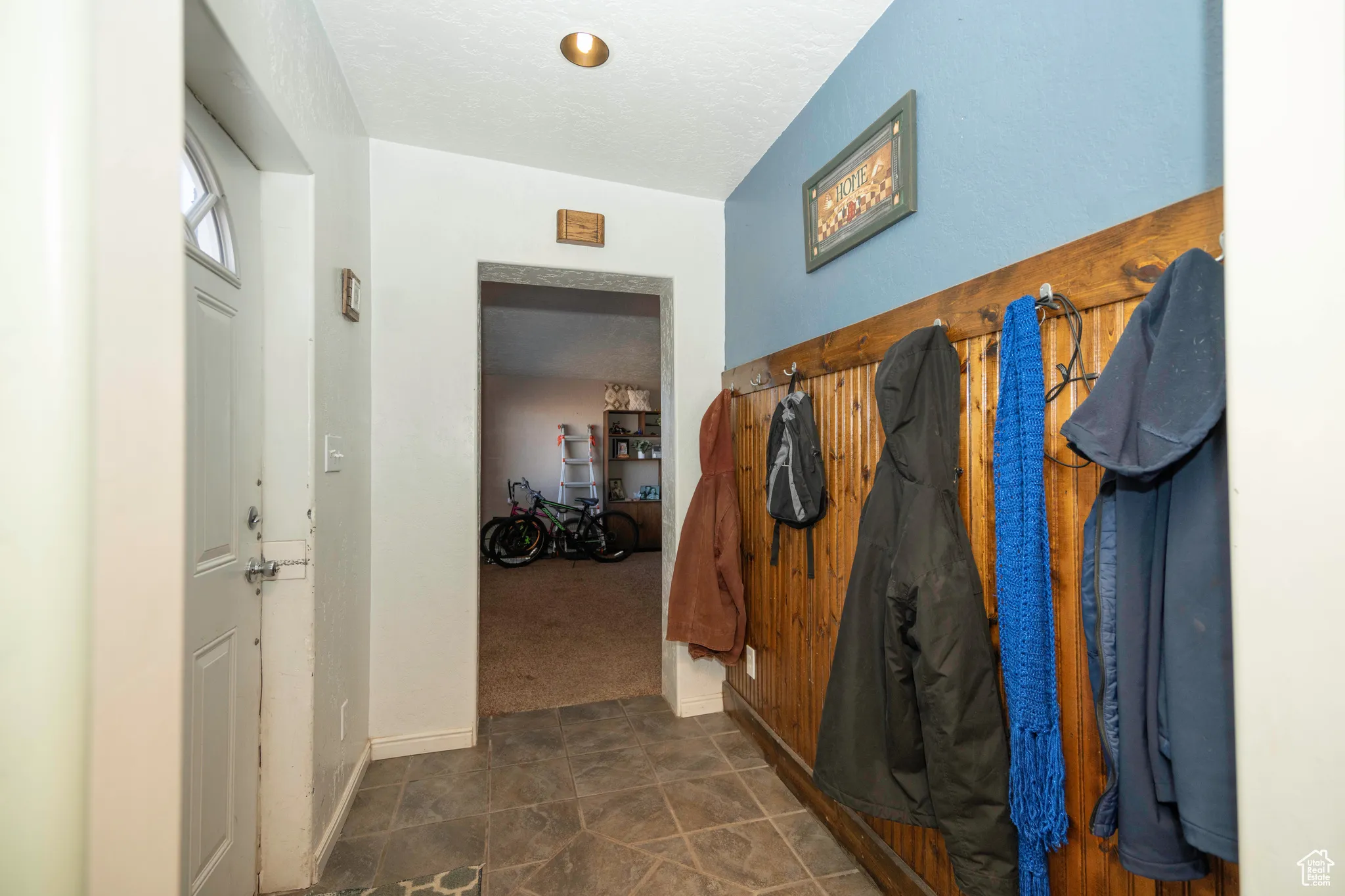 Hall featuring a textured ceiling and dark colored carpet
