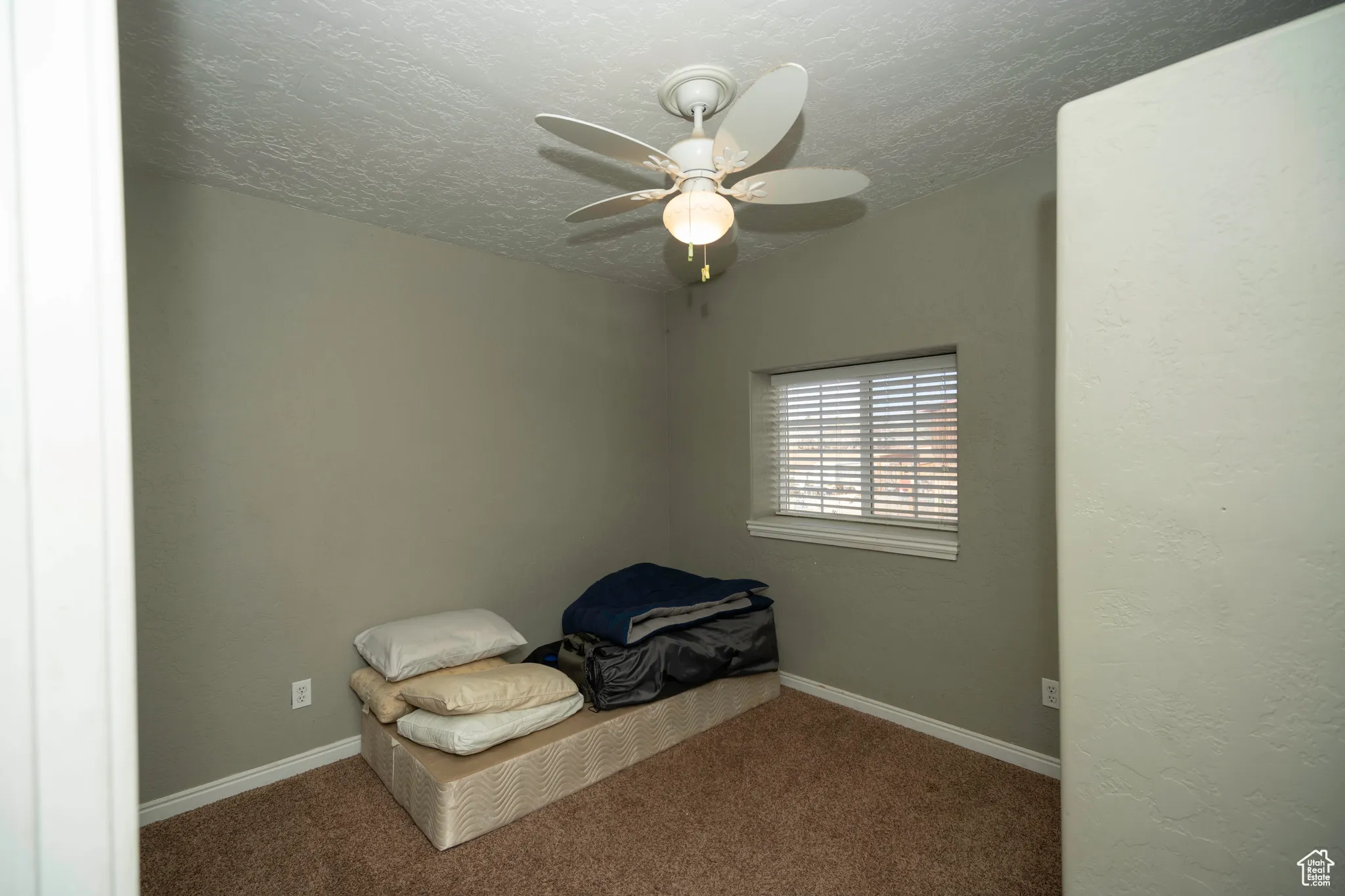 Unfurnished bedroom with ceiling fan, carpet floors, and a textured ceiling