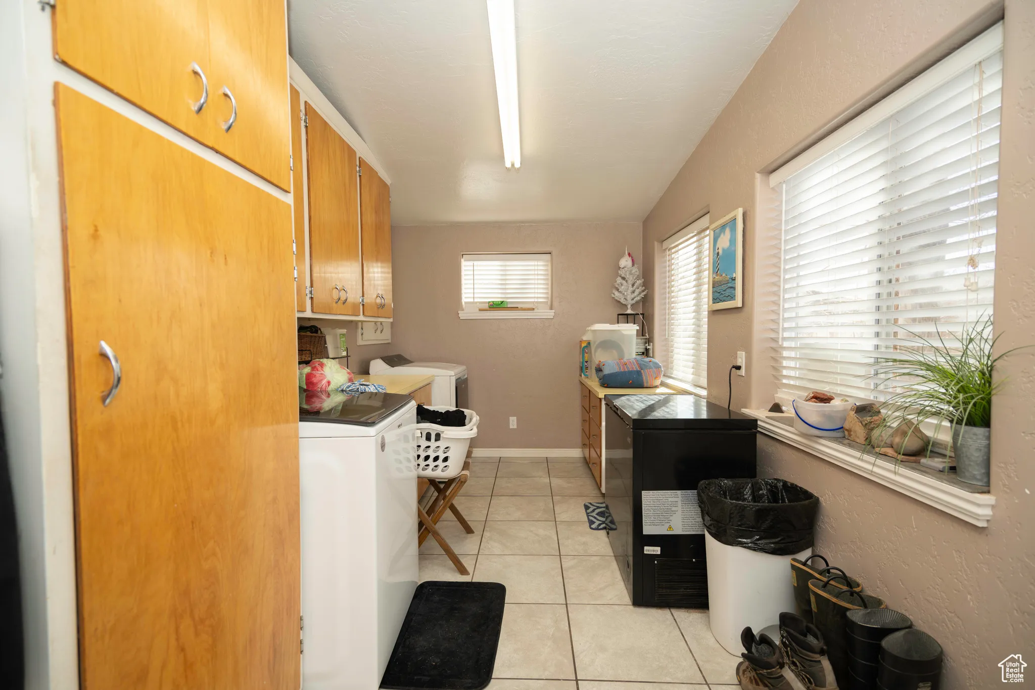 Interior space with cabinets, washing machine and dryer, and light tile patterned floors